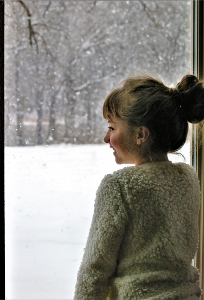 imagen de portada del artículo sobre eficiencia entre calefactor y bomba de calor en la que aparece una niña mirando por una ventana al exterior que está nevado
